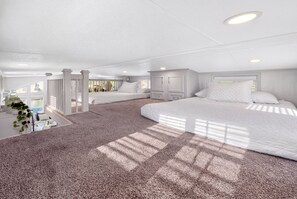 A hotel room with a large bed, a smaller bed, a seating area with a view, and a balcony with plants.