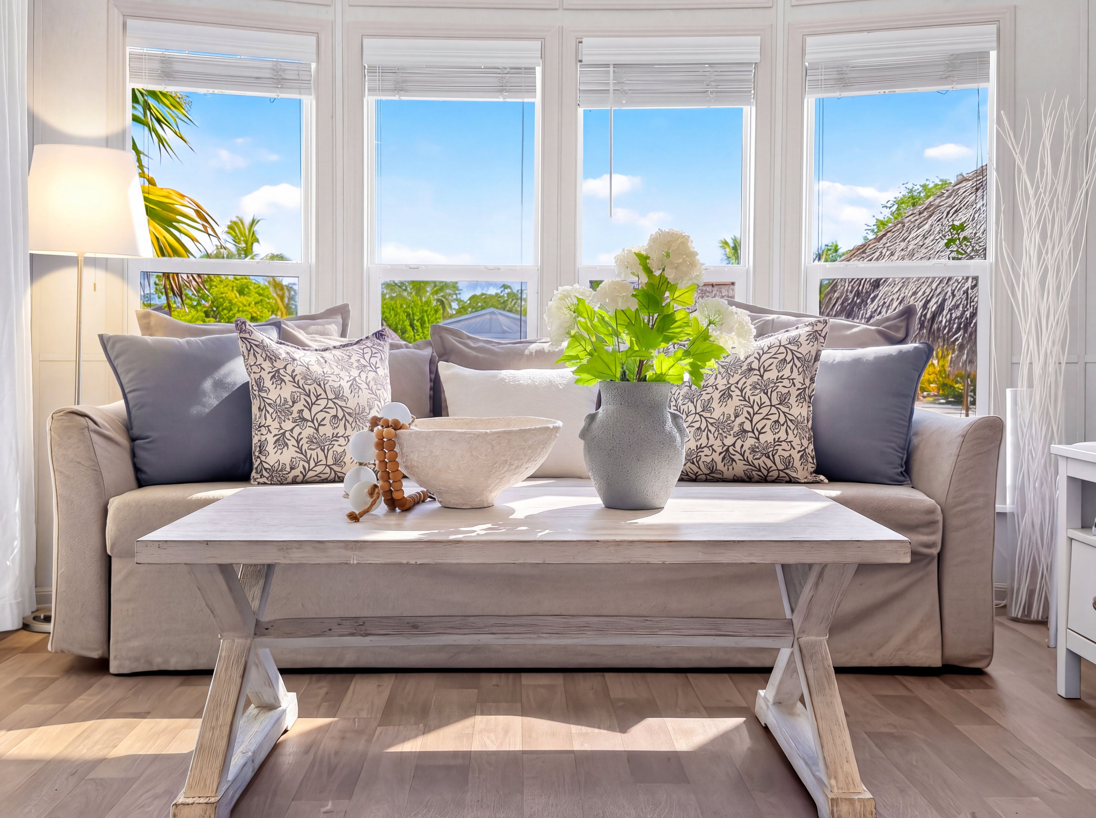 Ein modernes Wohnzimmer mit einer Couch, einem Couchtisch und Blick ins Freie durch große Fenster.