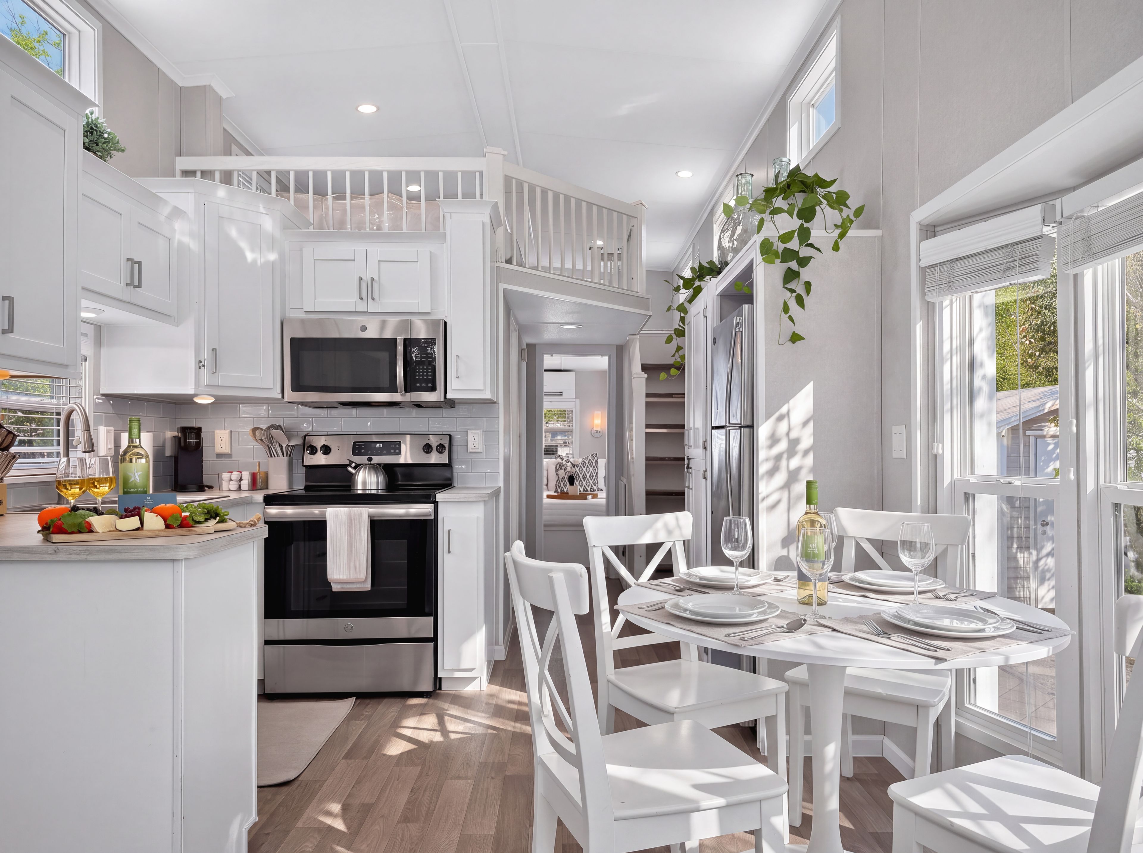 A modern kitchen with white cabinetry, a built-in microwave, and a dining area with a white table set for four.