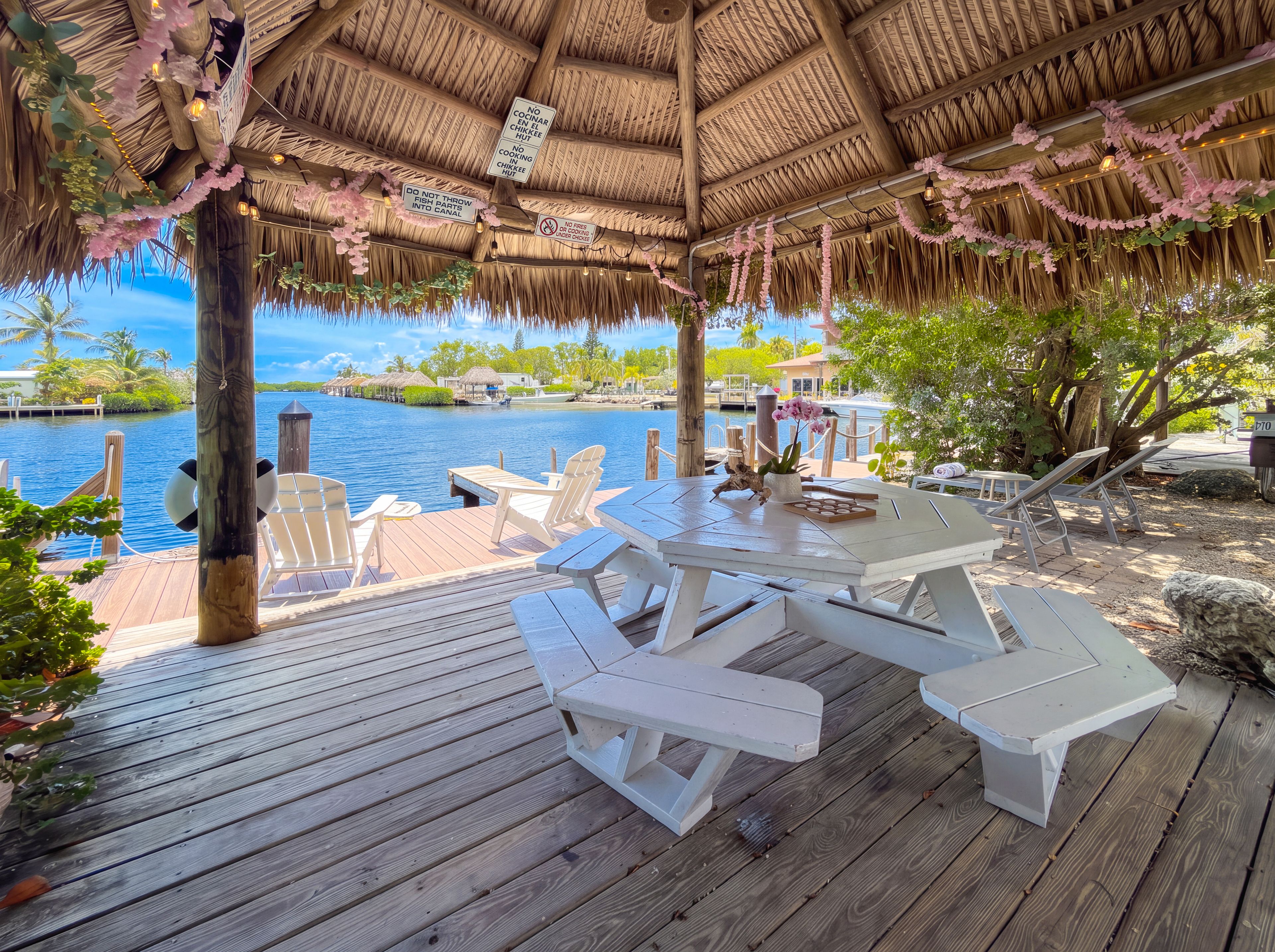 A wooden deck with picnic tables and chairs overlooking a body of water.