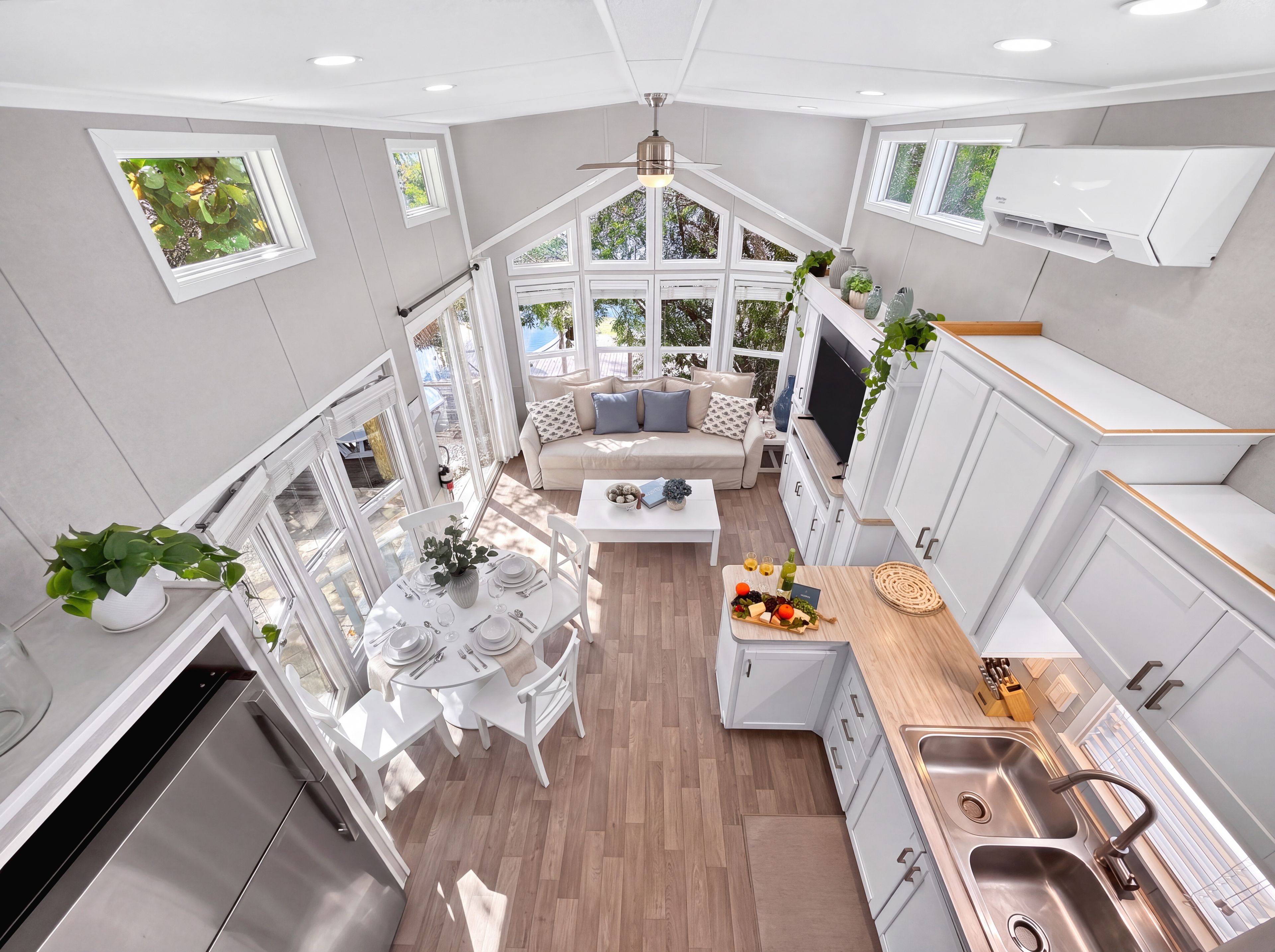 A modern kitchen with white cabinetry, a dining area with a round table, and a built-in TV.