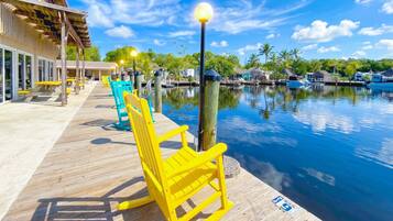 A wooden deck with yellow chairs, a pool, and a building with a covered area.