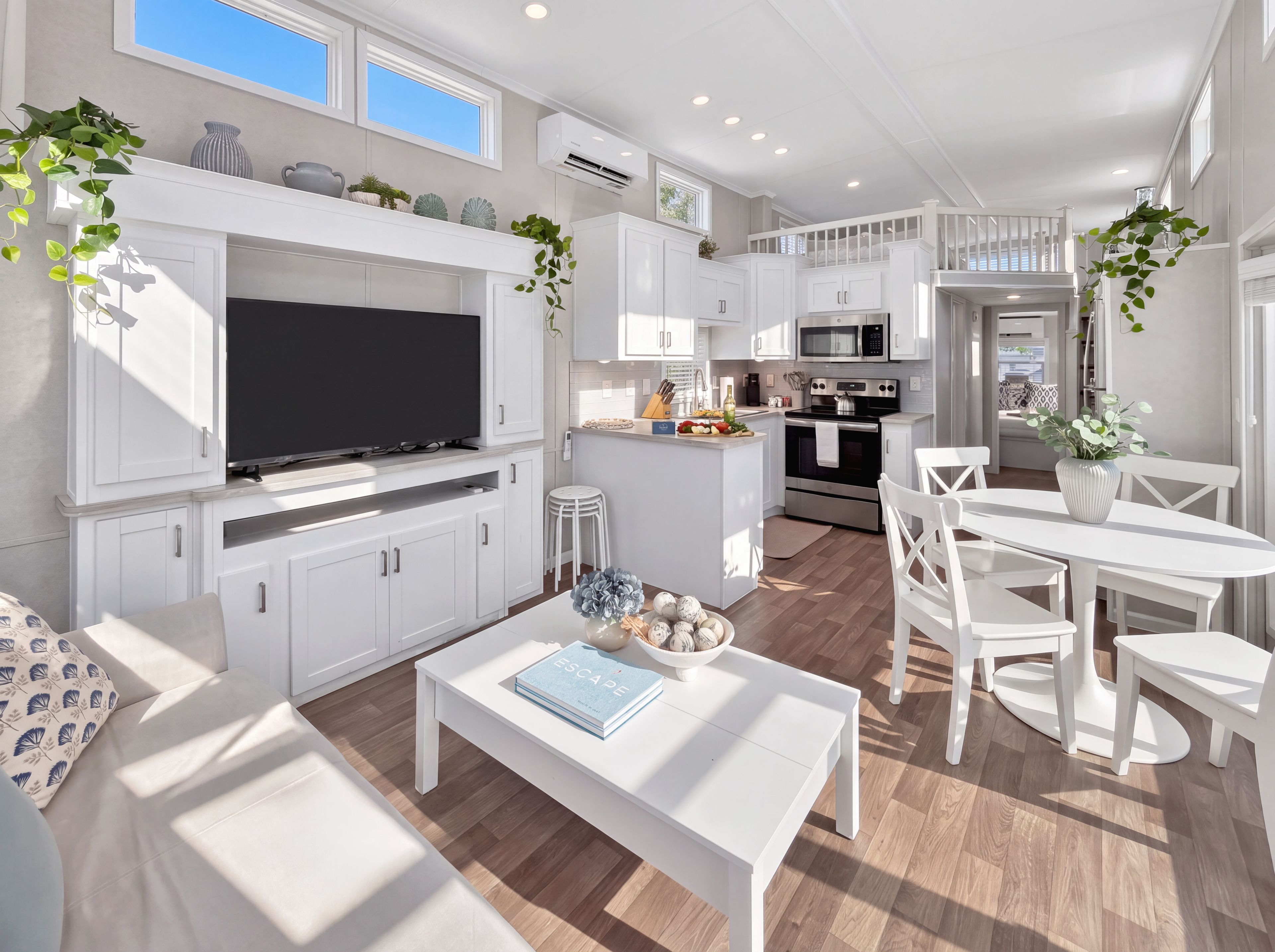 A modern kitchen with white cabinetry, a central island, and a dining area with white furniture.