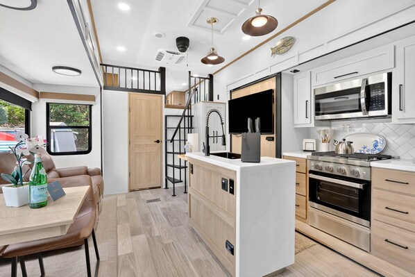 A modern kitchen with a microwave, oven, and a small island. - Brand New 2025 RV 2BR + 2 Lofts, 2BA Pool & Marina (Key Largo)