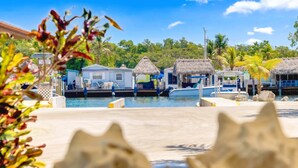 Un puerto deportivo con bungalows sobre el agua, un muelle y un cielo azul despejado.