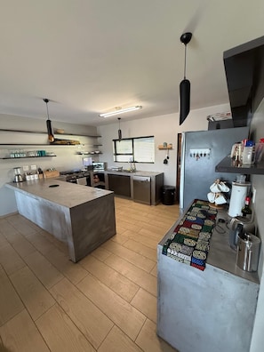 Una cocina moderna con una isla central, un refrigerador y una ventana con persianas.