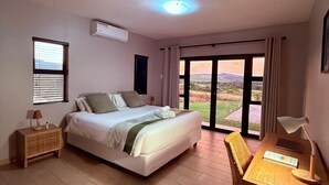 Un dormitorio con cama, escritorio, silla, ventana y vistas al exterior.