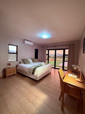 Un dormitorio con cama, escritorio, silla, ventana y vistas al exterior.