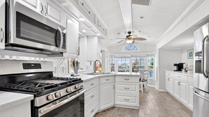 Une cuisine moderne avec des meubles blancs, une cuisinière encastrée, un four à micro-ondes et un grand îlot central doté d’un évier.
