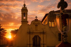 A church with a bell tower, a cross, and a door, set against a sunset sky. - Loft 15-min walk to Banorte Stadium (Ciudad de México)
