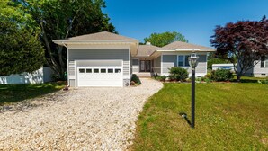 Une maison à deux étages avec un garage, un porche à l’avant et une pelouse bien entretenue.