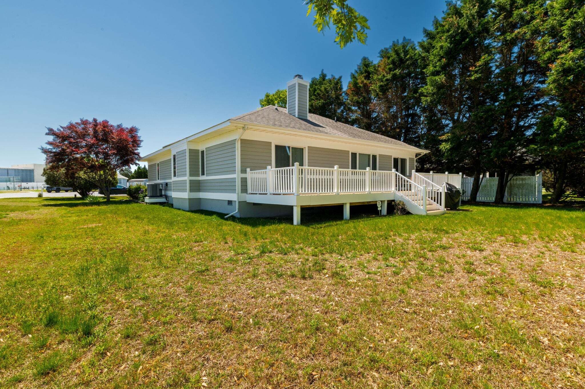 A single-story house with a covered porch, a chimney, and a small deck.
