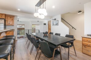 Une cuisine moderne avec un coin repas, des meubles en bois et un escalier.