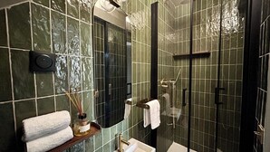 Ein Badezimmer mit einer gläsernen Duschkabine, einem Waschbecken mit Goldarmatur und einem Spiegel darüber.