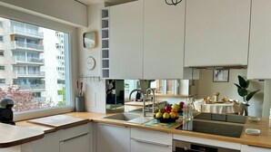 Et moderne køkken med indbygget ovn, vask og et vindue med udsigt over et boligområde.