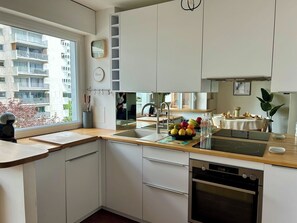 Eine moderne Küche mit Einbauofen, Spüle und Fenster mit Blick auf eine Wohngegend.