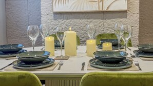 A dining table set with plates, glasses, and candles, with a textured wall and a decorative panel in the background. - Forest Inspired Home! Near M1 and Superb Locations (Nottingham)