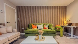 A modern living room with a green sofa, white coffee table, and a wooden slatted wall. - Forest Inspired Home! Near M1 and Superb Locations (Nottingham)