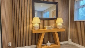 A wooden console table with two lamps, a decorative object labeled 'ABSTRACT,' and a mirror above it. - Forest Inspired Home! Near M1 and Superb Locations (Nottingham)