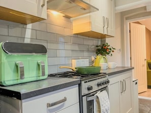 Una cocina con estufa verde, horno blanco y salpicadero de azulejos.