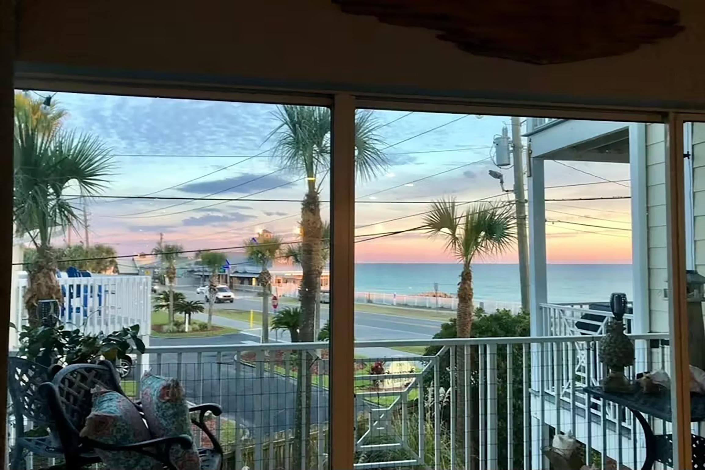 A balcony with a view of the ocean and street at sunset.