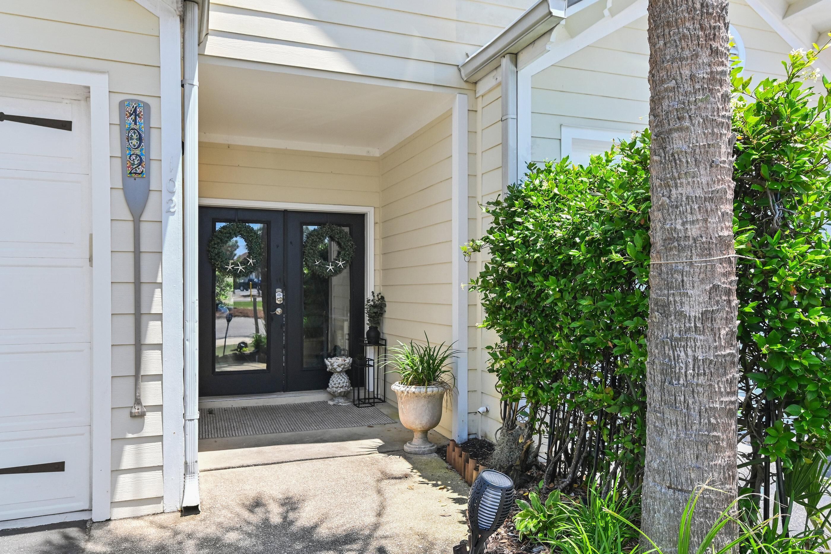 A house with a front door, a porch, a potted plant, and a tree.