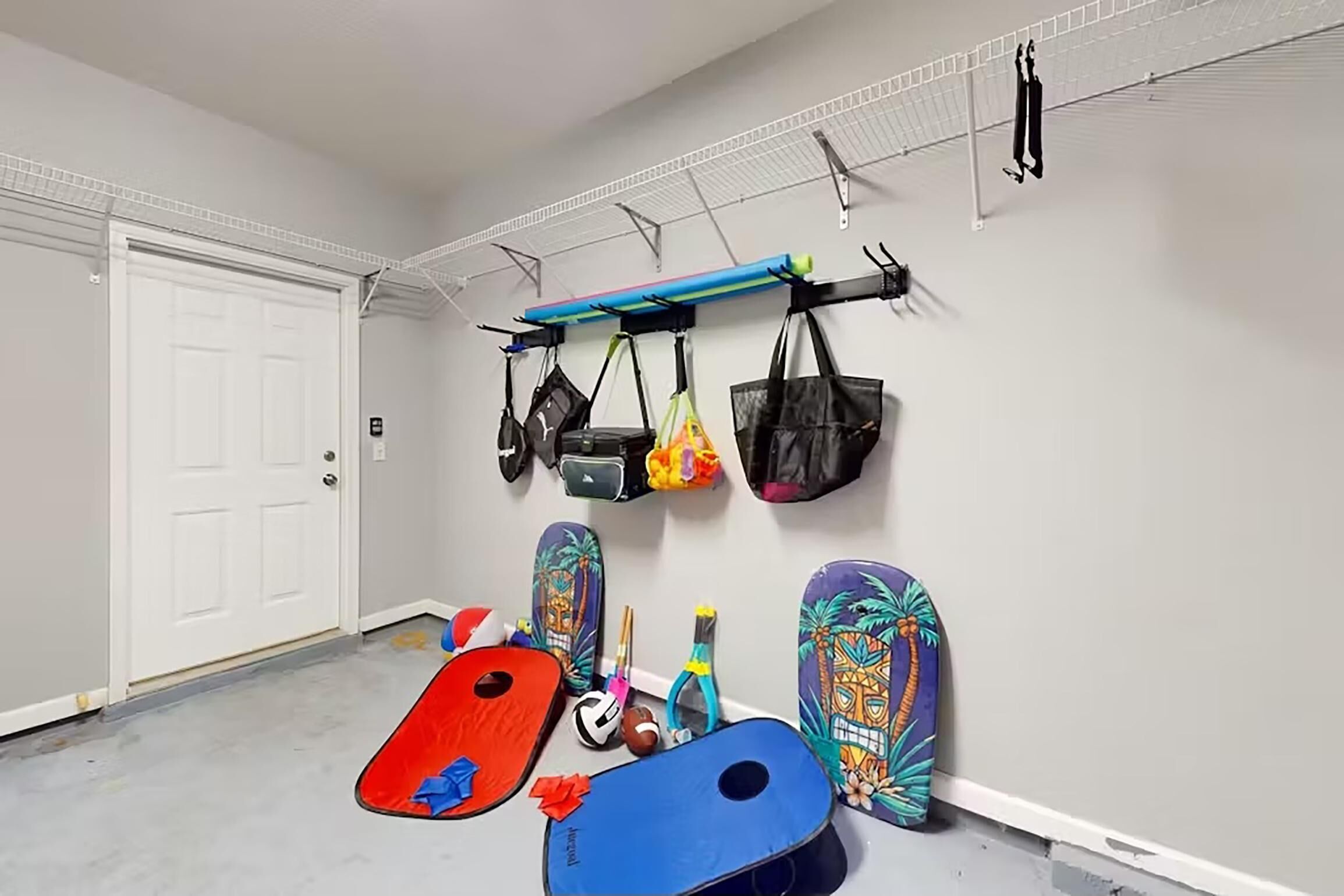 A room with a white door, a metal rack with bags, and two surfboards on the floor.