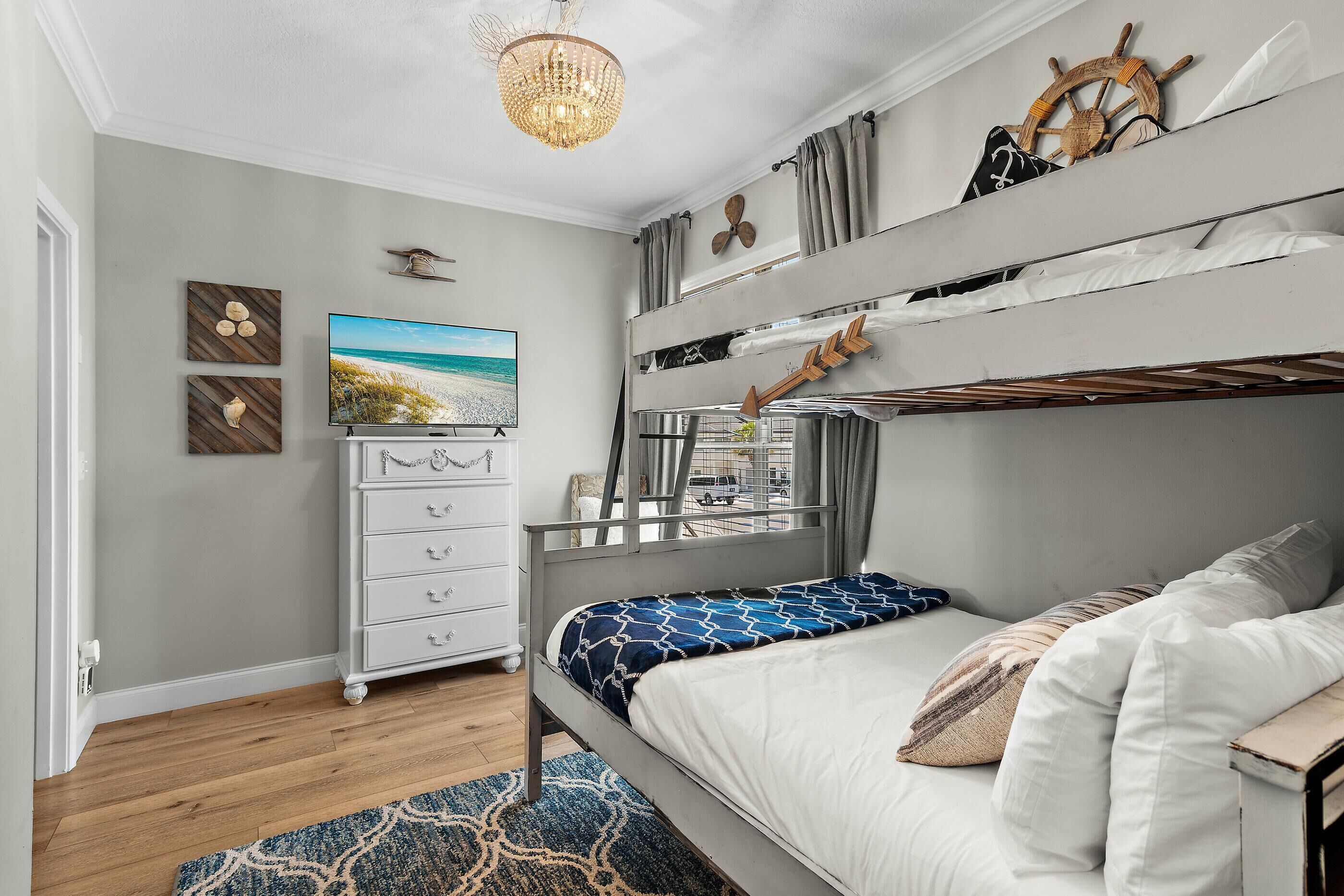 Ein Stockbett im Seestil, eine Kommode, ein Fernseher und ein Kronleuchter.