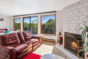 Un salón con sofá de cuero, chimenea y ventanas amplias.