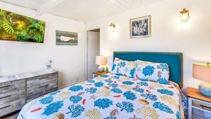 Un dormitorio con cama, cómoda de madera, mesita de noche y decoración en la pared.