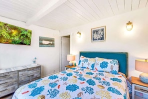 Une chambre à coucher comprenant un lit, une commode en bois, une table de chevet et des œuvres d’art murales.