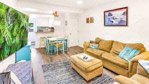 Una sala de estar con un sofá, un reposapiés y un comedor con una mesa y sillas.