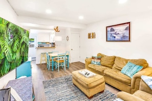 Un salon comprenant un canapé, un pouf et un coin repas avec une table et des chaises.