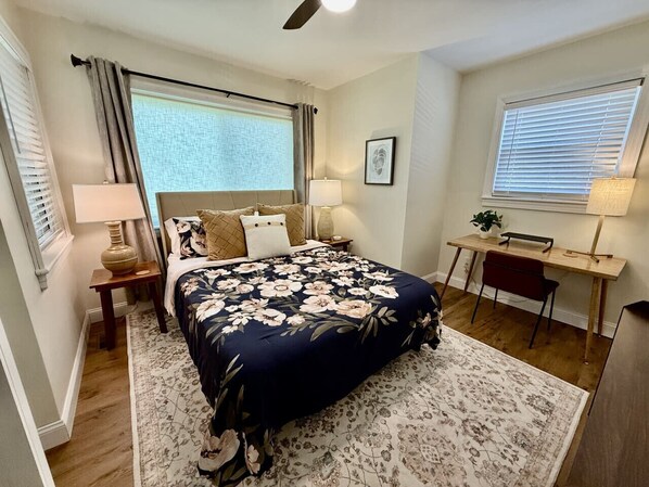 A bedroom with a bed, two bedside tables, a desk, and a chair.