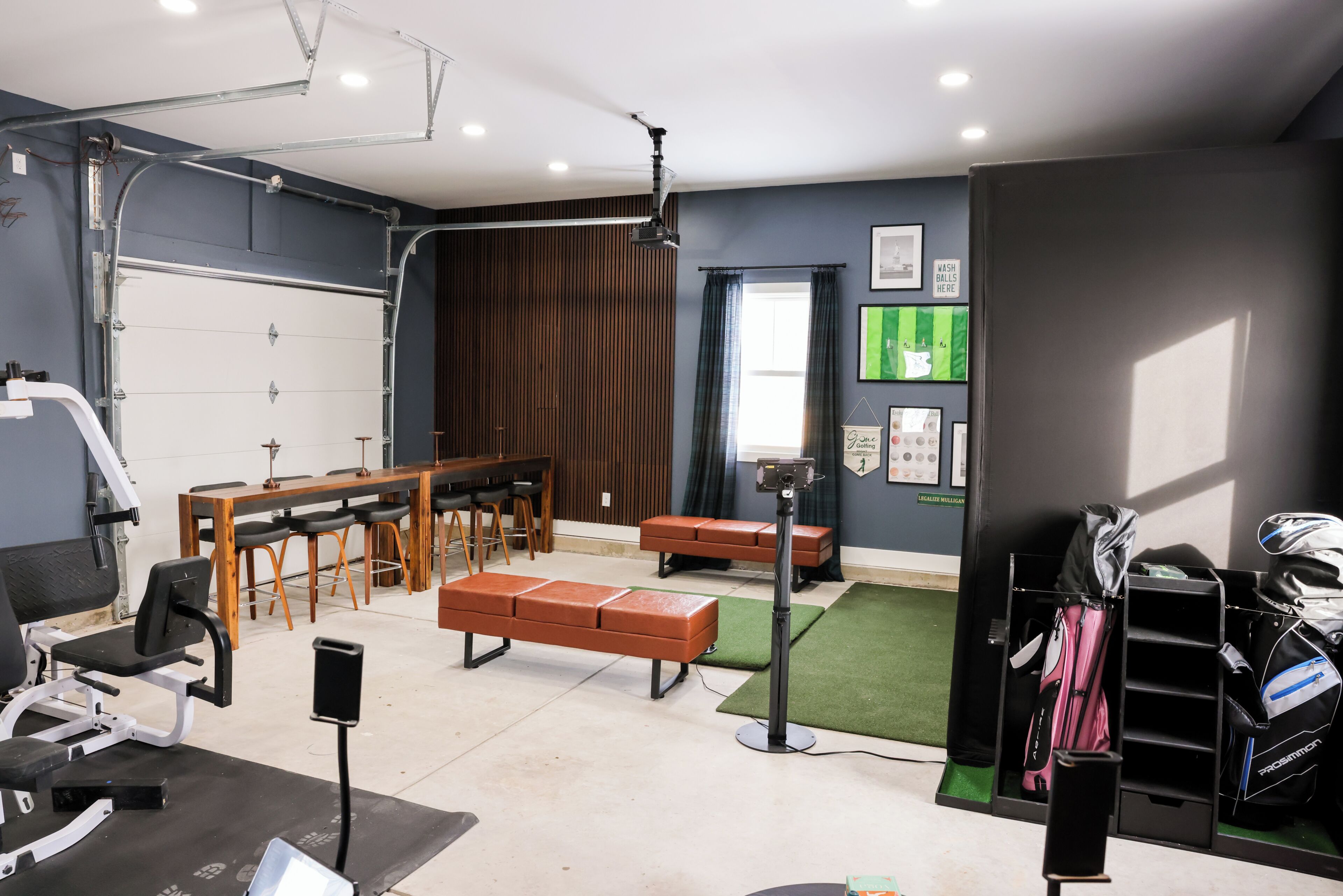 Ein Fitnessraum mit Trainingsgeräten, Bänken, Laufband und Golftaschenständer.