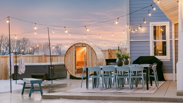 A patio with a wooden barrel, a table with chairs, string lights, and a grill. - Sleep 30, Near Grand Park, Golf Sim, Sauna, Hottub (Westfield)