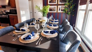 A dining table set for six with blue napkins, silverware, and wine glasses. - Sleep 30, Near Grand Park, Golf Sim, Sauna, Hottub (Westfield)