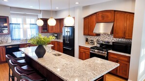 A modern kitchen with granite countertops, stainless steel appliances, wooden cabinets, and pendant lighting. - Sleep 30, Near Grand Park, Golf Sim, Sauna, Hottub (Westfield)