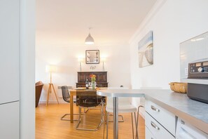 A modern kitchen with a built-in oven, a dining area with a table and chairs, and a pendant light. - Larus, Holiday Apartment Smoke House Quay, Milford Marina, Sleeps 4, 2 bedrooms,  bathrooms (Milford Haven)