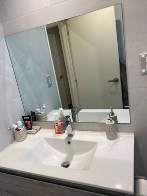 Un baño con un espejo grande, dos lavamanos y distintos artículos de tocador.