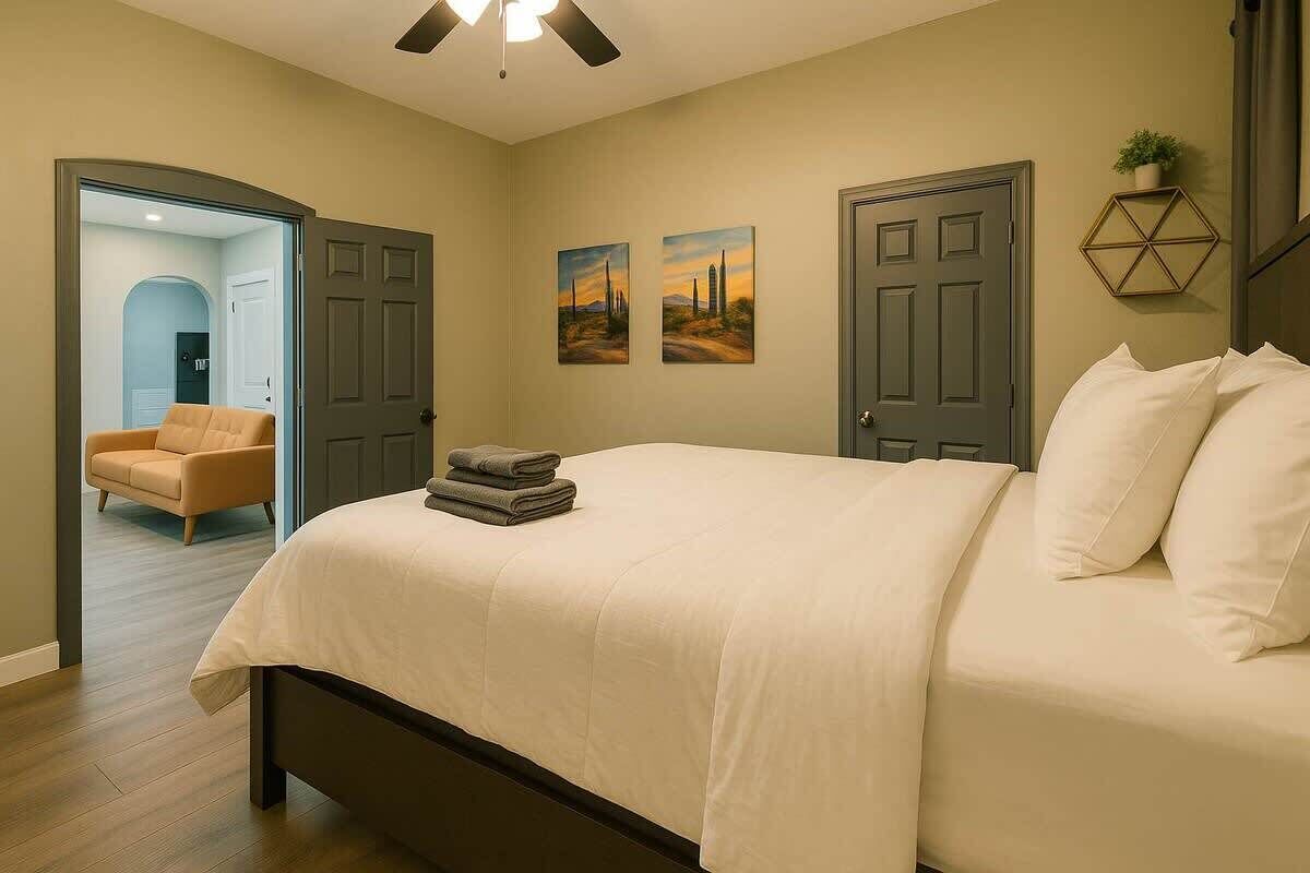 A bedroom with a bed, two doors, a chair, and two paintings on the wall.