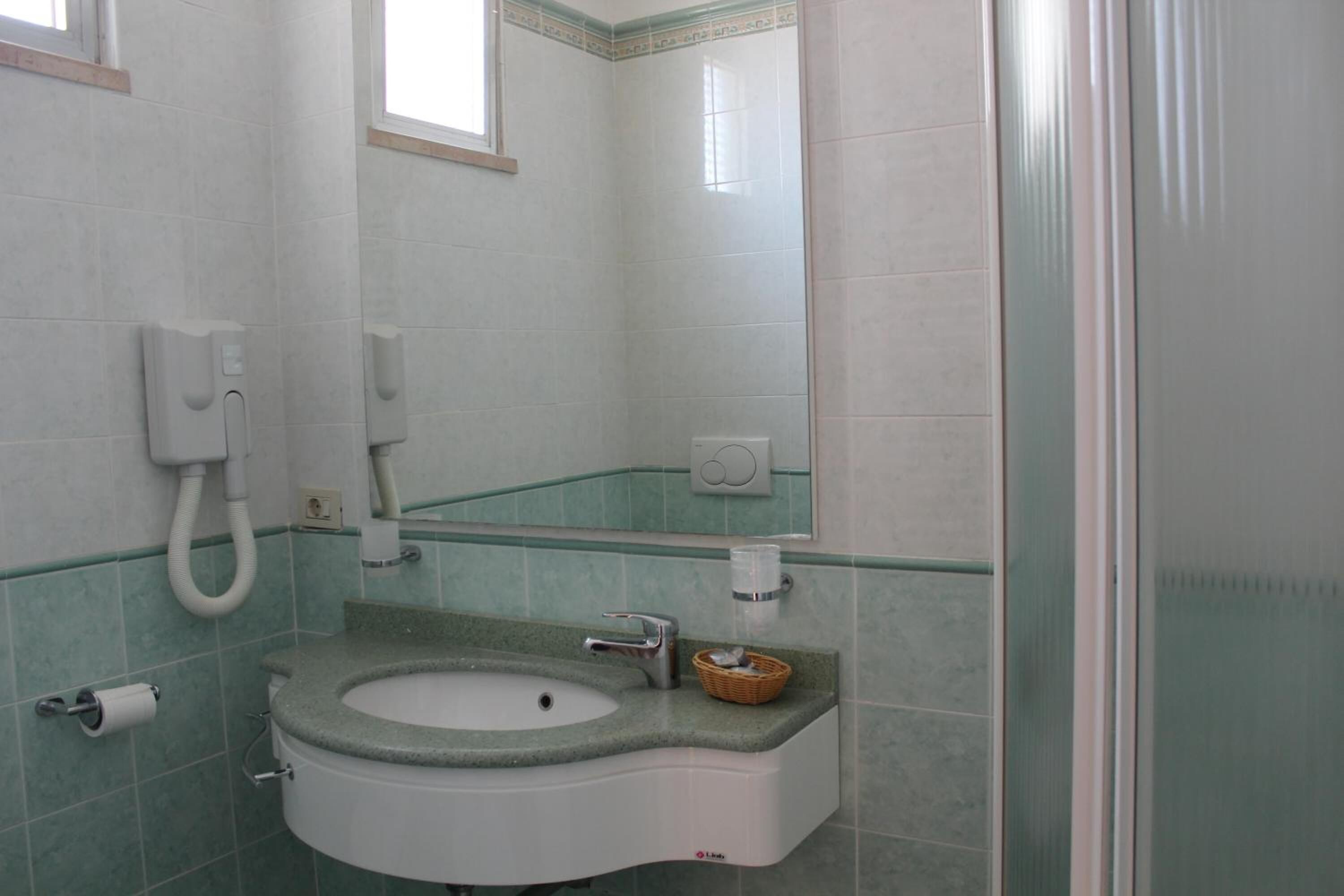 Une salle de bain équipée d’un lavabo, d’un miroir et d’un sèche-mains.