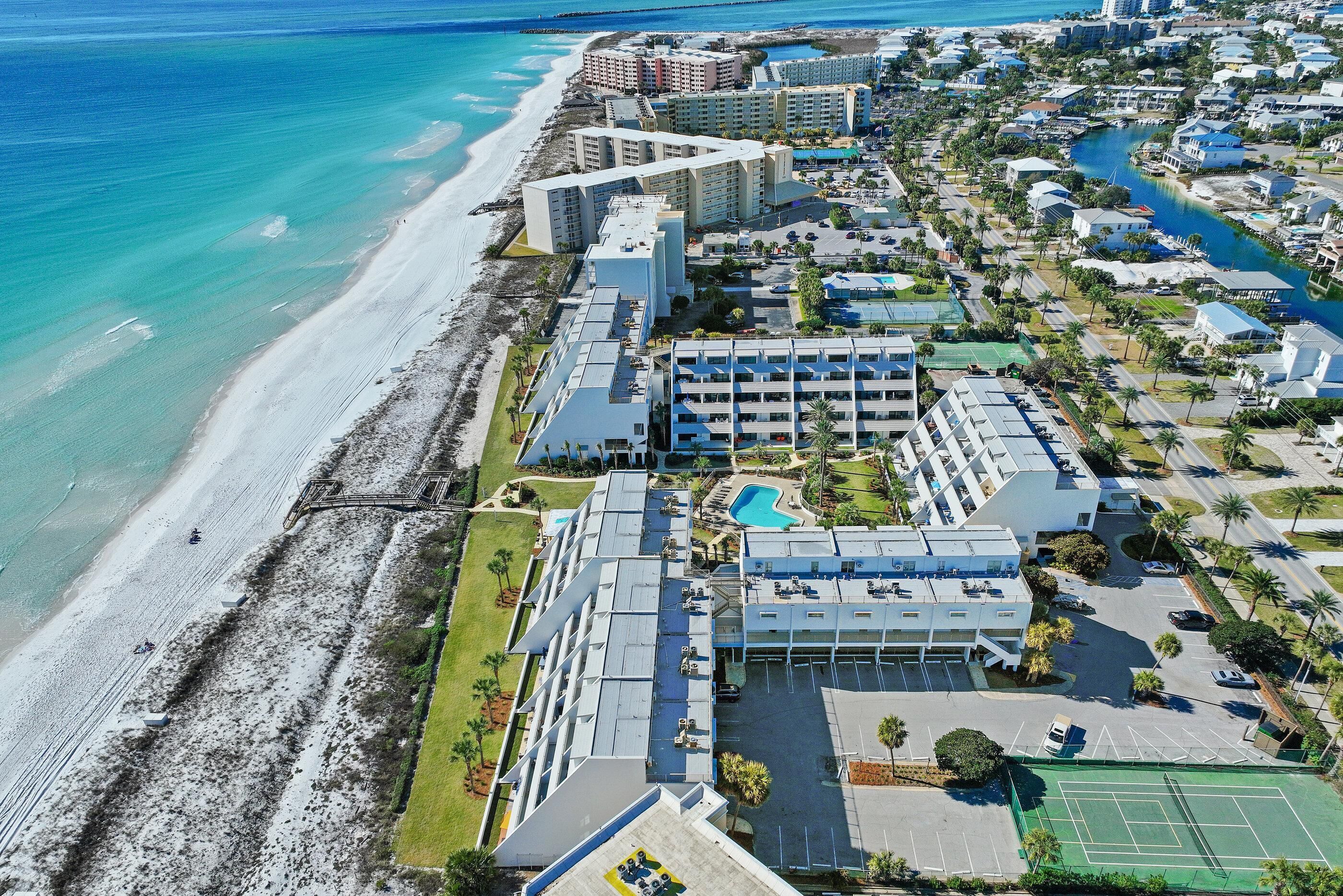 An aerial view of a coastal hotel with multiple buildings, a beach, and a swimming pool.