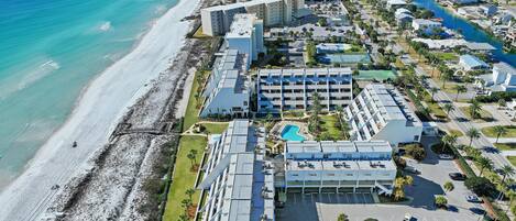 An aerial view of a coastal hotel with multiple buildings, a beach, and a swimming pool.
