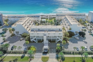 A hotel with a central courtyard, multiple floors, and a view of the ocean. - Aegean 220 (Destin)