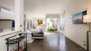 Ein modernes Interieur mit Küche, Essbereich und Wohnbereich, mit großen Fenstern und Blick auf Grünflächen.