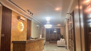 A hotel reception area with a marble floor, a reception desk, a chandelier, and a large window. - Hotel Grand Matoa Timika (Timika)