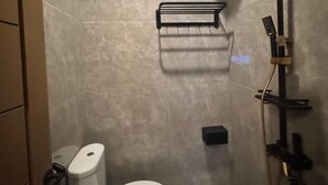 A bathroom with a toilet, a shower, and a towel rack. - Hotel Grand Matoa Timika (Timika)