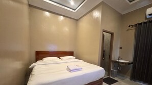 A hotel room with a large bed, a bedside table, a built-in sink, and a ceiling light fixture. - Hotel Grand Matoa Timika (Timika)