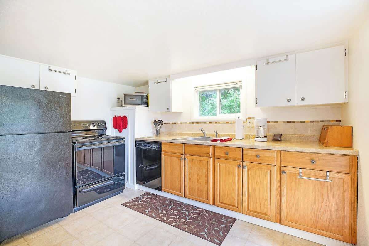 A kitchen with a refrigerator, oven, microwave, sink, and wooden cabinets.